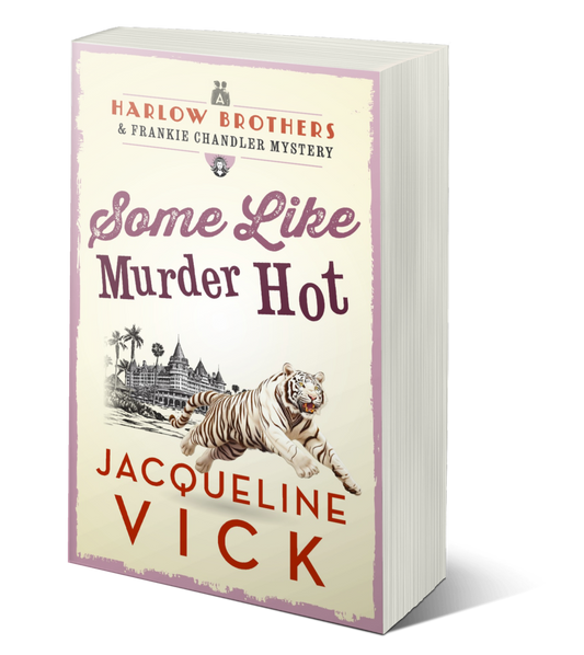 Paperback book cover for Some Like Murder Hot. A white tiger jumping in front of an old, beachside hotel. A Harlow Brothers & Frankie Chandler Mystery by Jacqueline Vick. 